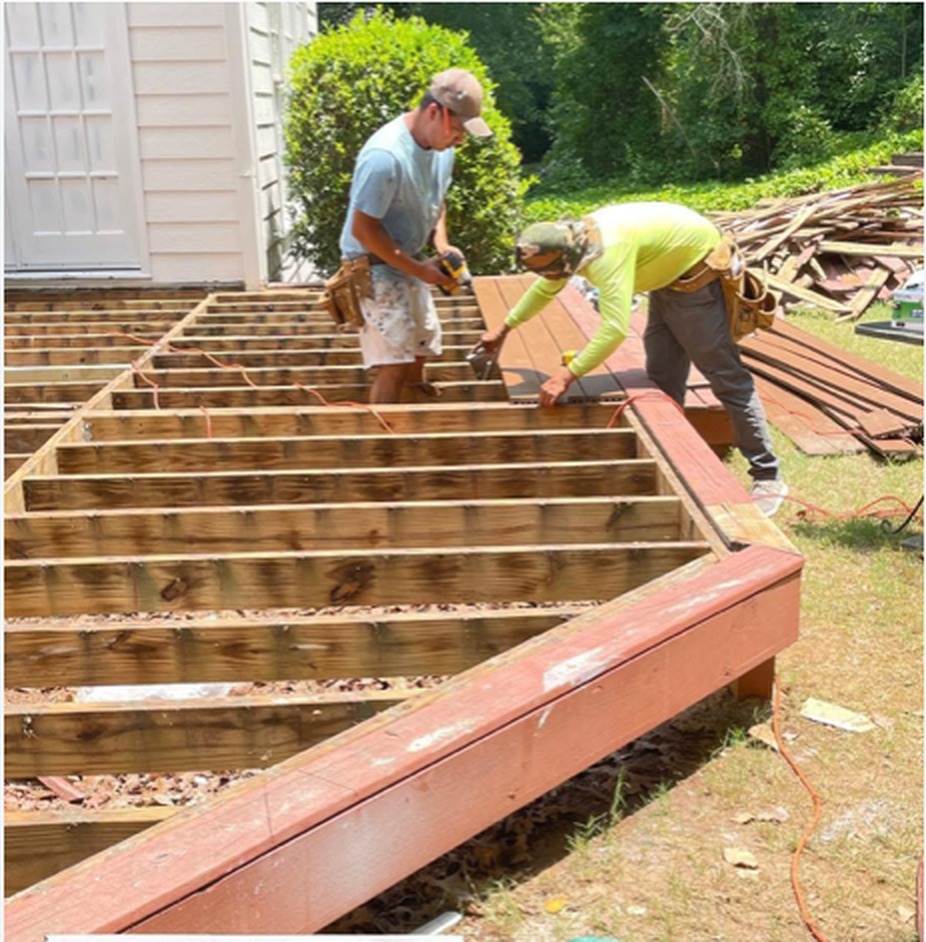 Creativo Painting crew members removing rotted deck boards and installing new decking over the framing